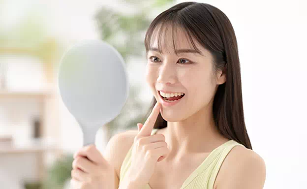 歯を鏡で確認する女性の画像