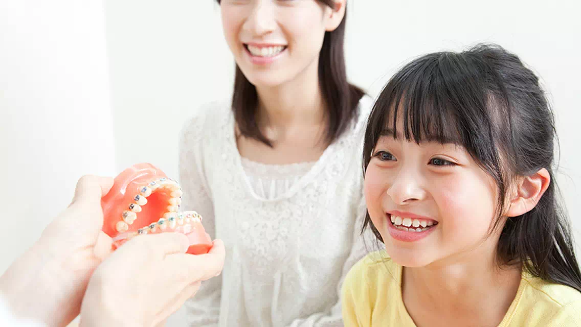 笑顔の子供が歯の説明を受けている画像